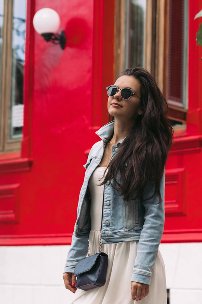 woman in sunglasses walks through the city streets - Foto, afbeelding