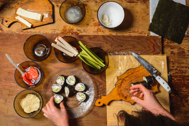 The woman cooked sushi and placed them on a round plate - Photo, Image