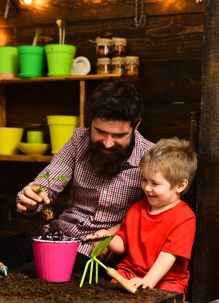 Father and son. Family day. Greenhouse. bearded man and little boy child love nature. happy gardeners with spring flowers. Flower care watering. Soil fertilizers. Look at it - Zdjęcie, obraz