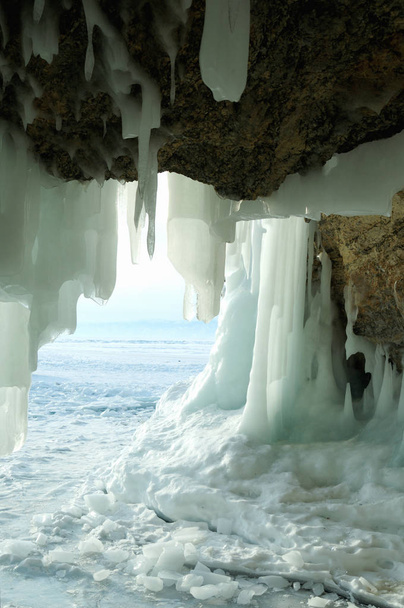 氷の洞窟からの眺め。凍った、クリスタルクリアな水滴は、鍾乳石のような滴が天井からハングアップします。昇る太陽が氷を染めた。部分的に着色された写真。中央のオブジェクトに焦点を当てます。被写界深度の超浅い. - 写真・画像