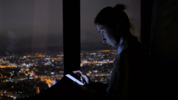 Kobieta używająca pionowego czarnego smartfona w nocy - Materiał filmowy, wideo