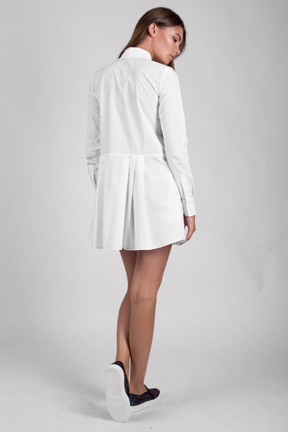 jong mooi brunette meisje poseren in studio dragen wit jurk  - Foto, afbeelding