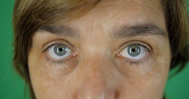 4k-boze blik, gefrown wenkbrauwen van een volwassen vrouw, grijs blauwe ogen, Slow Motion - Foto, afbeelding