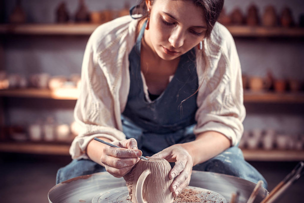 Bellissimo scultore artigiano lavora con argilla su una ruota Potters e a tavola con gli strumenti. Lavori manuali
. - Foto, immagini