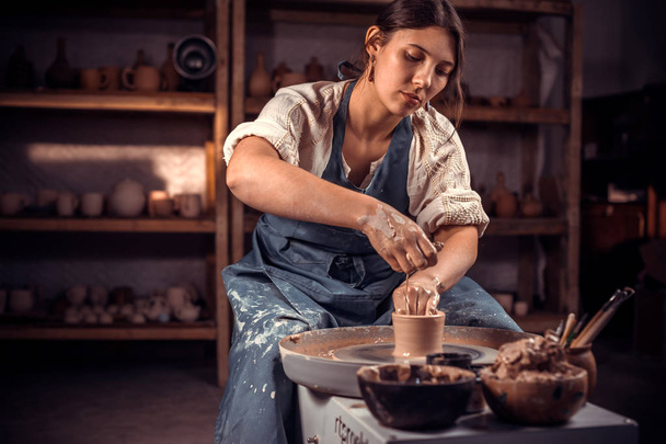 美しい陶芸家の彫刻家は、ポッターズホイールとツールでテーブルに粘土で動作します。クラフト生産. - 写真・画像