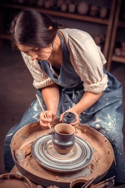 Mujer de cerámica con estilo sentado en el banco con rueda de cerámica y haciendo olla de barro. Artesanía nacional
. - Foto, Imagen