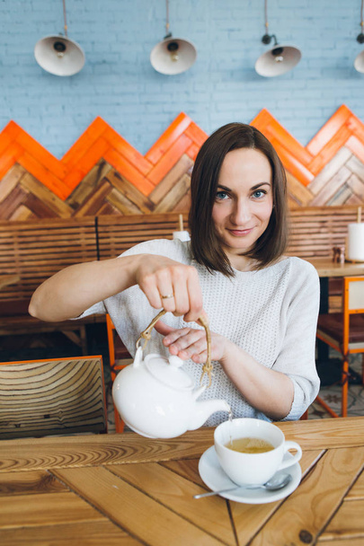 Woman pours green tea from a teapot into a Cup in a cafe - Fotoğraf, Görsel