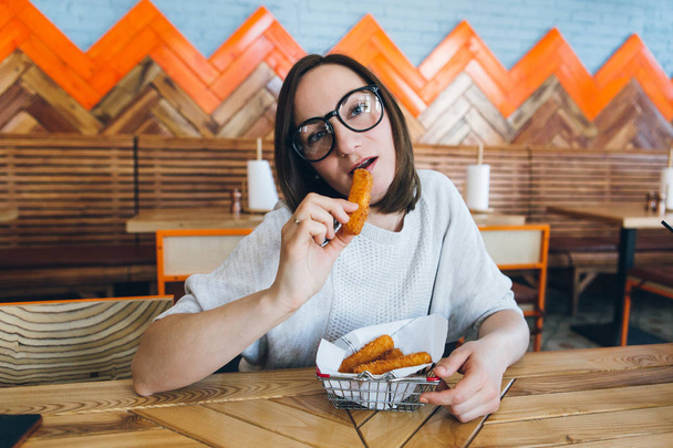 Woman eats fried cheese sticks in a cafe - 写真・画像