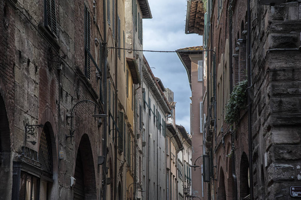 Узкая улица с типичными итальянскими домами в Lucca, Tuscany, Italy
 - Фото, изображение