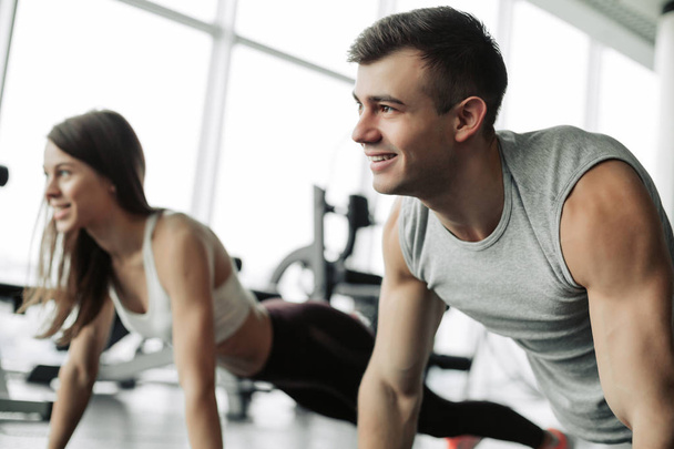 Sporty young couple doing plank exercise in gym - Photo, Image
