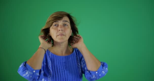 4k-egy elegáns nő kiegyenesíti a haját a zöld képernyőn a stúdióban - Felvétel, videó