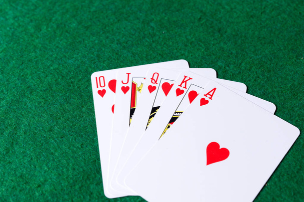 Yeşil arka planda kalplerin Kraliyet floş. Poker iskambil kağıtları kazanan eller - Fotoğraf, Görsel