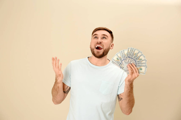 Portrait of emotional young man with money on color background - Φωτογραφία, εικόνα
