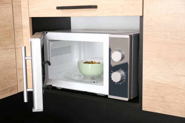 Open modern microwave oven with dish in kitchen - Fotografie, Obrázek