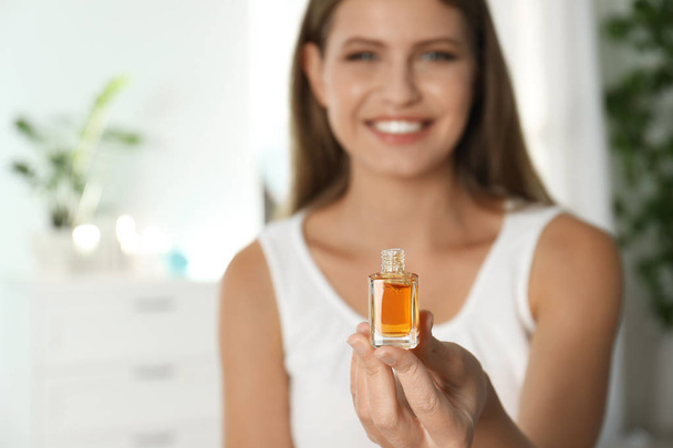 Young woman holding eyelash oil indoors, closeup - Fotografie, Obrázek