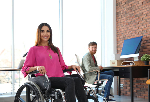 Young woman in wheelchair with colleague at office - Valokuva, kuva