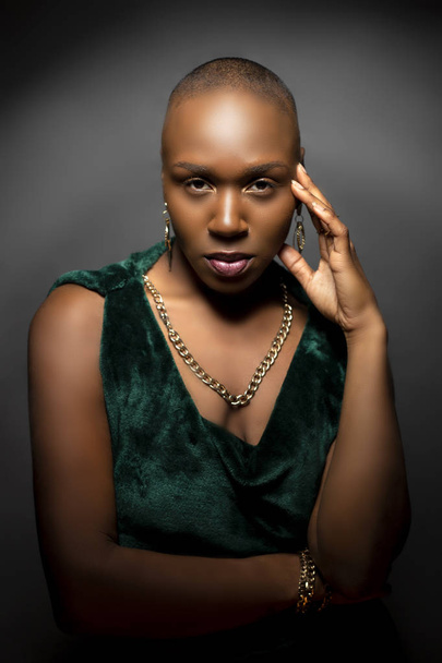 Black African American female fashion model with a bald hairstyle in a studio.  The portrait shows the beauty and confidence of the bold and trendy glamour hairdo style.   - Фото, изображение