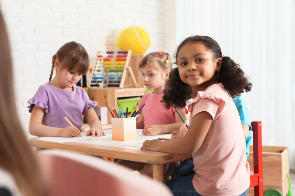 Niños adorables dibujando juntos en la mesa en el interior. Actividades en el jardín de infantes
 - Foto, Imagen