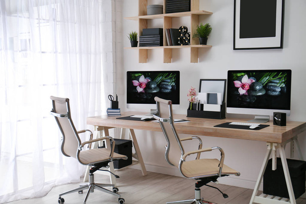 Modern munkahely nagyméretű íróasztallal és számítógépekkel a szobában. Stílusos enteriőr - Fotó, kép