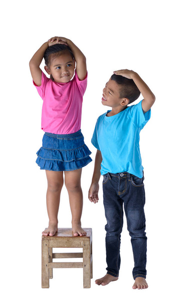 Niño y niña midiendo su altura aislados en bac blanco
 - Foto, imagen