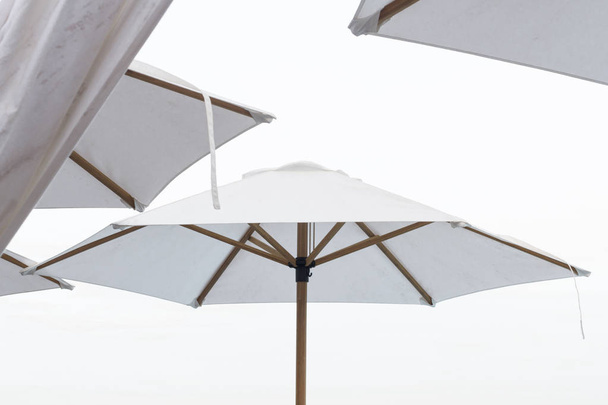 Letní den na pláži s bílými deštníky. - Fotografie, Obrázek