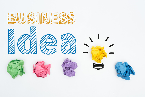 top view of business idea inscription near colorful crumpled paper balls on white background, business concept - Photo, Image