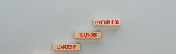 Panoramaaufnahme von Holzklötzen mit Führung, Teamwork, Beitragswörtern auf grauem Hintergrund, Geschäftskonzept - Foto, Bild