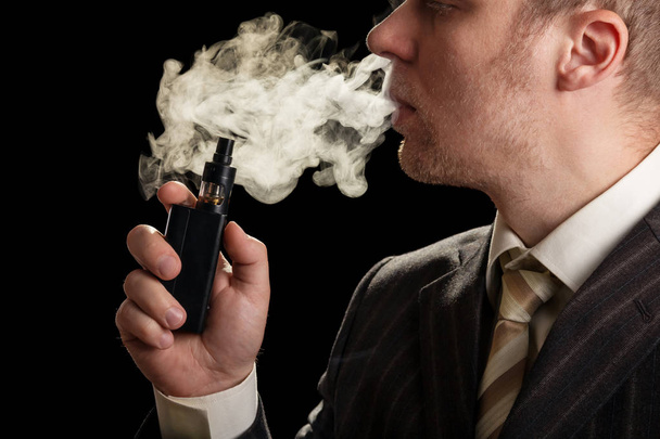 Business man with the electronic cigarette and steam isolated on black - Fotoğraf, Görsel