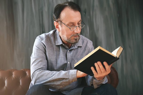 Красивий зрілий чоловік читає книгу вдома
 - Фото, зображення