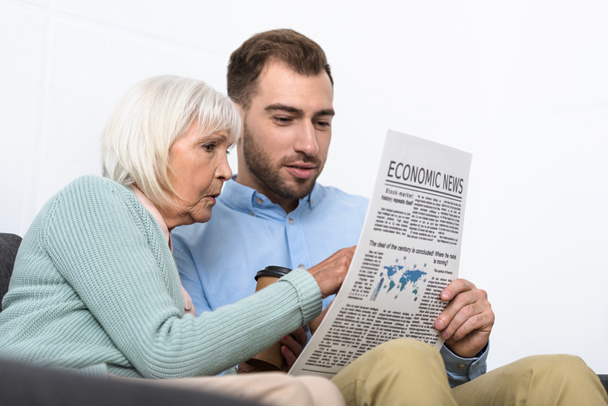 man and senior mother reading newspaper at home - Foto, afbeelding