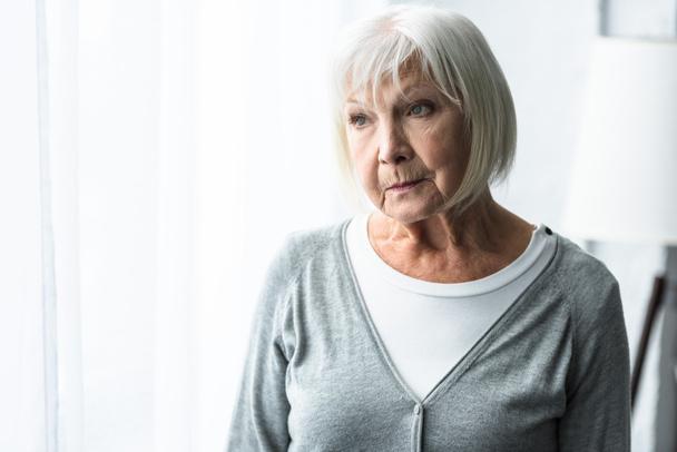 pensive senior woman in grey cardigan looking away - Fotoğraf, Görsel
