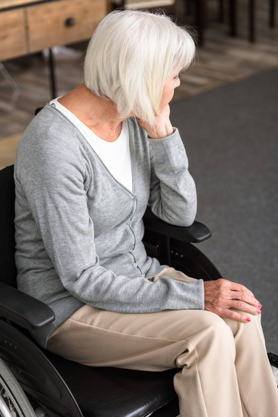 sad disabled senior woman sitting on wheelchair and looking away - Photo, Image