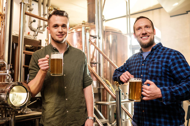 Двое мужчин пробуют свежее пиво на пивоварне
 - Фото, изображение