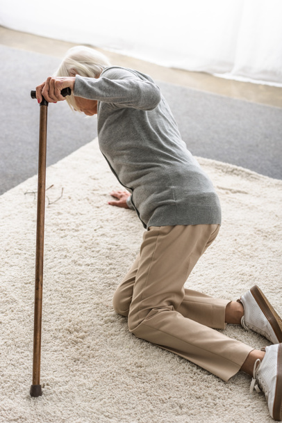 sick senior woman with wooden cane fallen on carpet - Photo, Image