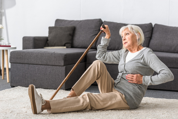 kärsivä vanhempi nainen, jolla on sydänkohtaus istuu matolla
 - Valokuva, kuva