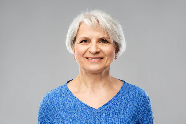 portrait of smiling senior woman in blue sweater - Foto, afbeelding