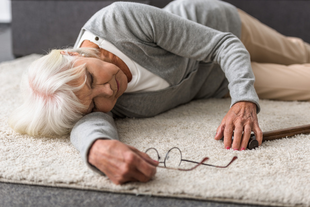 malade femme âgée avec des lunettes couché sur le tapis
 - Photo, image