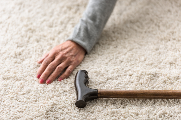cropped view of senior woman with cane on carpet - Foto, Imagen