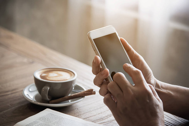 Man using mobile phone while drinking coffee and reading book in coffee shop - modern life style people in coffee shop concept - Photo, Image