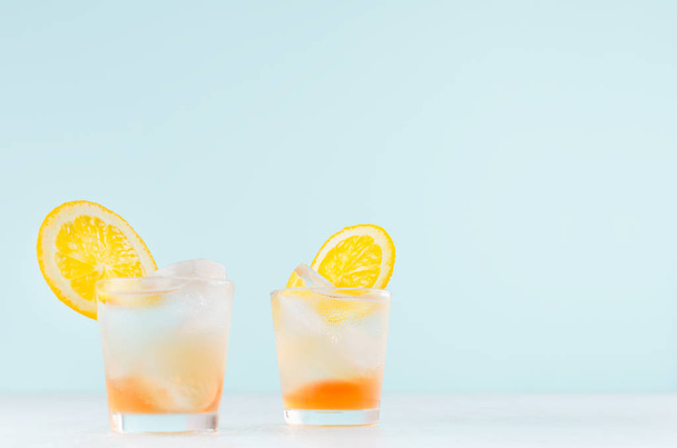 Summer fresh alcoholic drinks with oranges liquor, ice cubes in shot glass on blue wall, copy space. - Фото, зображення