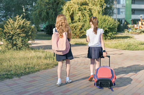 Вид ззаду, дві дівчинки школярки йдуть до школи з рюкзаками
 - Фото, зображення