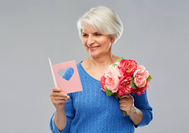 happy senior woman with flowers and greeting card - Foto, Bild