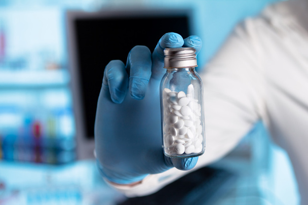 χέρι του φαρμακοποιού δίνοντας ένα μπουκάλι χάπια - Φωτογραφία, εικόνα