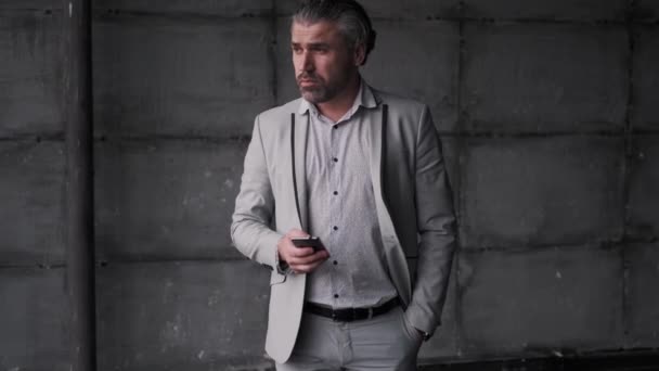 Porträt eines Mannes mittleren Alters im Businessanzug. Geschäftsmann mit Smartphone in der Hand. - Filmmaterial, Video