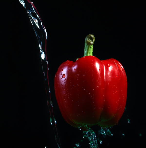 Gevlekte water op de rode peper. op een zwarte achtergrond - Foto, afbeelding