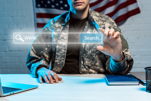 bijgesneden weergave van militaire man in uniforme gebaren in de buurt van zoeken belettering in adresbalk - Foto, afbeelding
