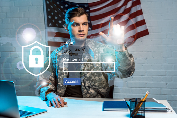 όμορφος στρατιώτης με ομοιόμορφη δείχνοντας με το δάχτυλό σας στο login και γράμματα κωδικού πρόσβασης στο γραφείο  - Φωτογραφία, εικόνα
