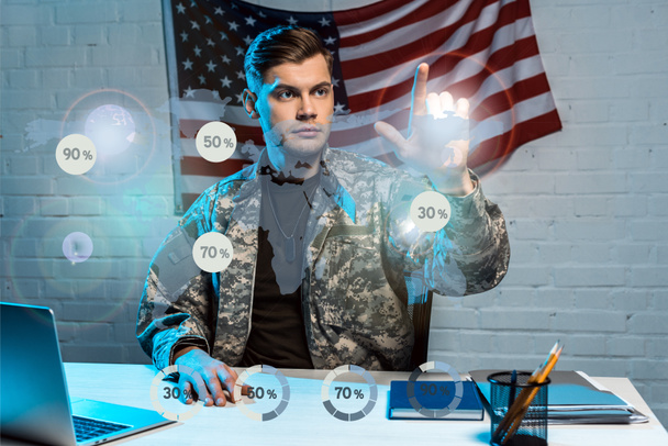 schöner Soldat in Uniform, der mit dem Finger auf Prozentdiagramme zeigt - Foto, Bild