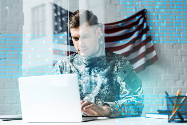 όμορφος στρατιώτης σε καμουφλάζ στολή χρησιμοποιώντας το laptop στο γραφείο κοντά απεικόνιση δεδομένων - Φωτογραφία, εικόνα