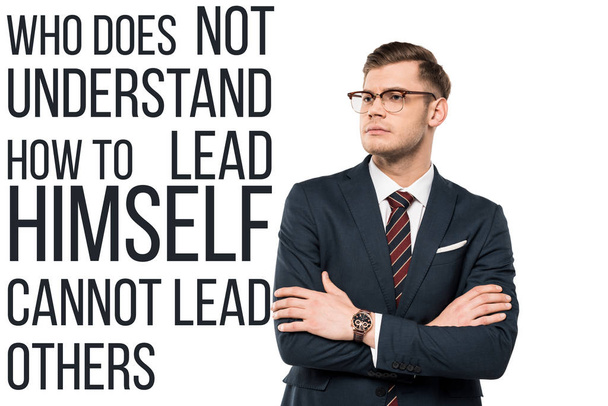 handsome businessman standing with crossed arms near who doesn't understand how to lead himself cannot lead others lettering on white  - Photo, Image